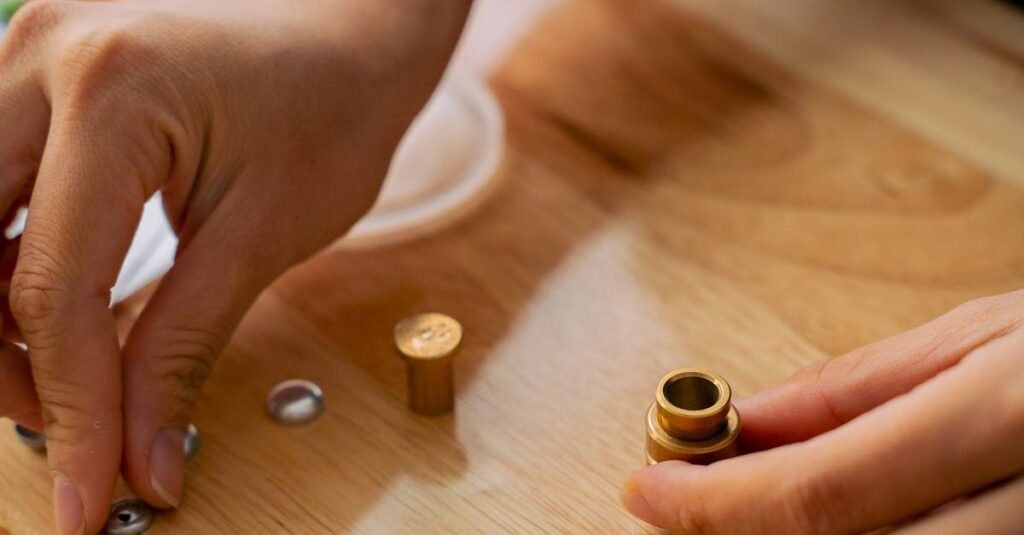 Detailed view of hands working with snap fasteners on a wooden table, showcasing sewing precision.